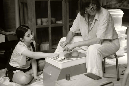 Mother and daughter working together at the pottery wheel